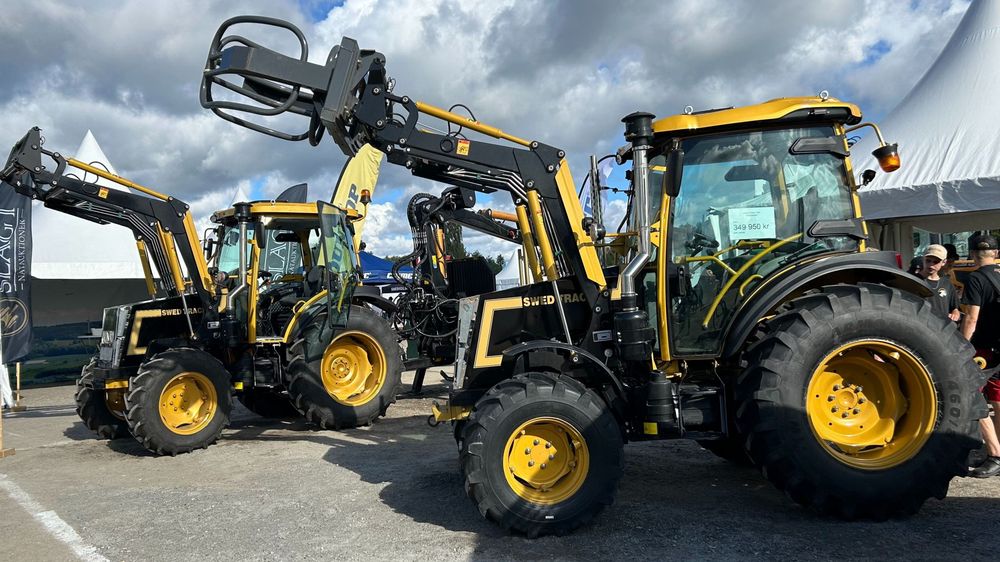 Two yellow tractors on a sunny day. 